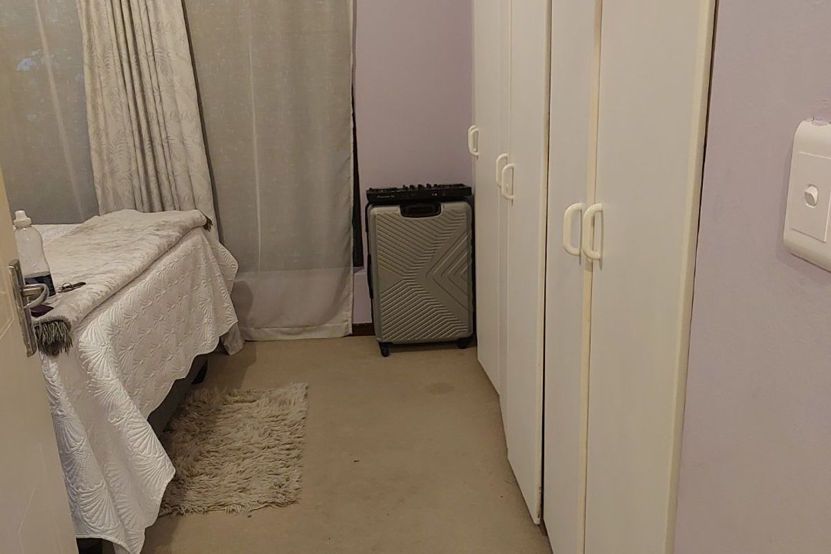 A bedroom featuring built-in cupboards and carpet flooring, providing functional storage space within the apartment.