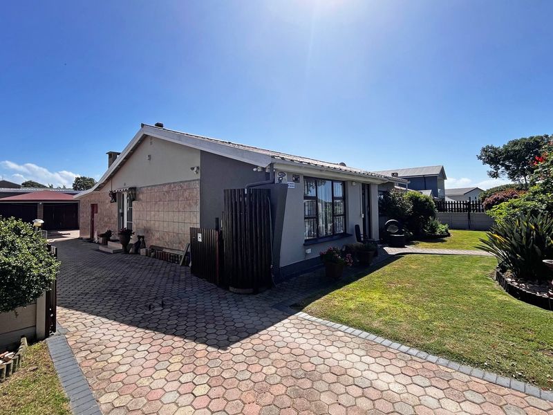 A well-maintained single-story home featuring a paved driveway, landscaped garden, and a combination of rendered and tiled exterior finishes.