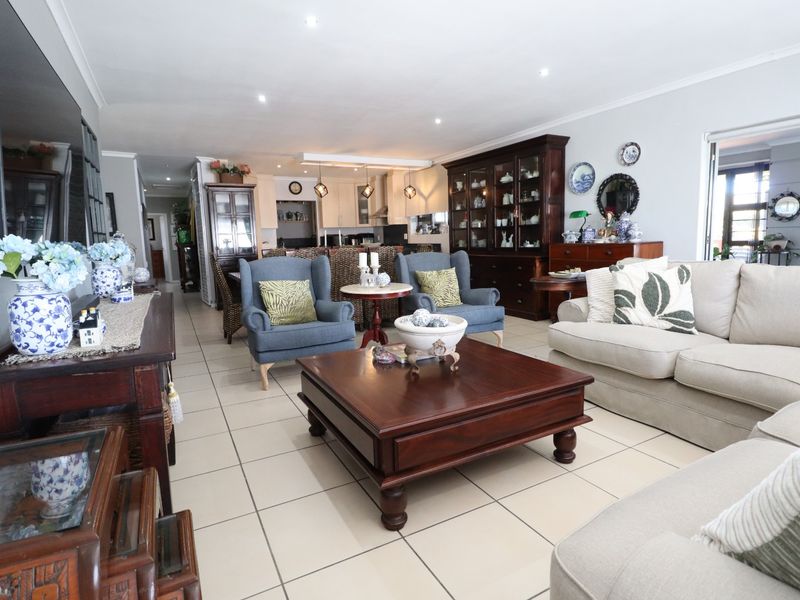 Spacious open-plan living and kitchen area featuring neutral ceramic floor tiles, recessed lighting, and a functional kitchen layout with an island.