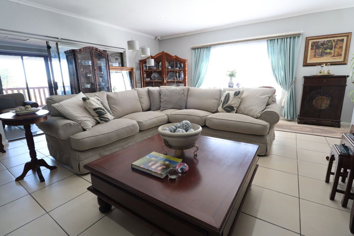 A spacious living room featuring neutral tiled flooring, large windows, and sliding glass doors that provide access to the outdoor area.