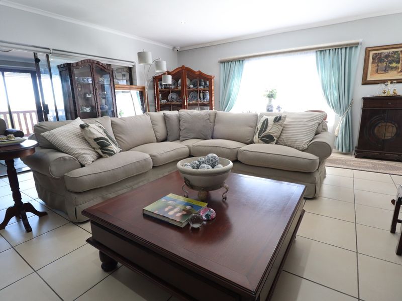 A spacious living room featuring neutral tiled flooring, large windows, and sliding glass doors that provide access to the outdoor area.