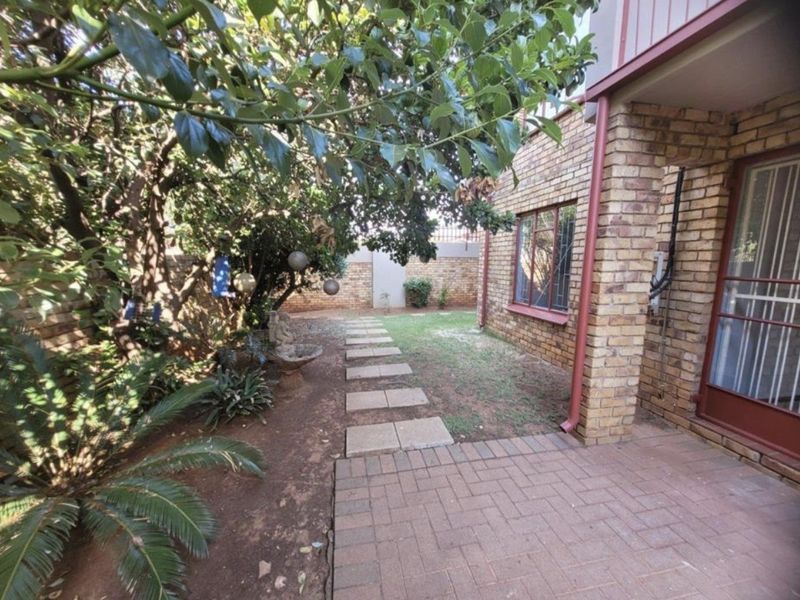 A private rear garden area featuring a brick facade, paved patio, and a stepping stone path leading through the landscaped yard.