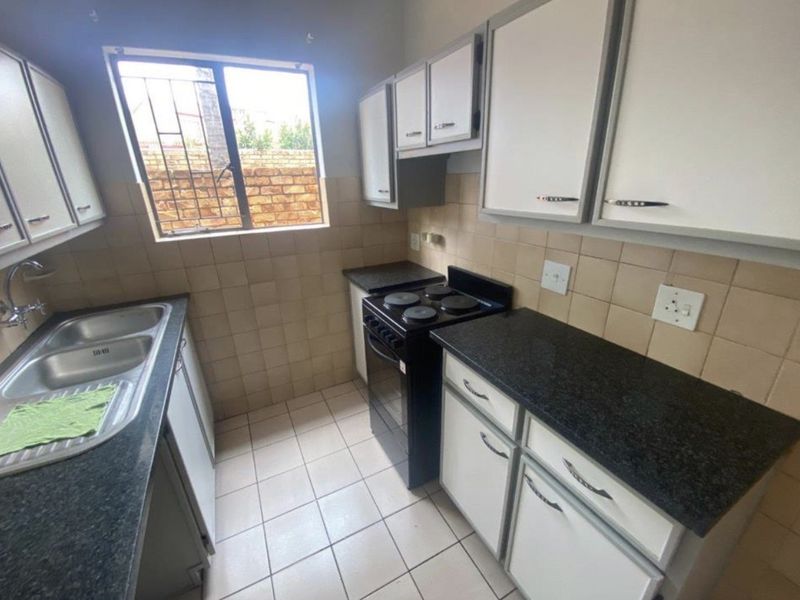 Functional kitchen featuring tiled splashbacks, laminate countertops, built-in cabinetry, and a freestanding stove, offering a practical layout for daily meal preparation.