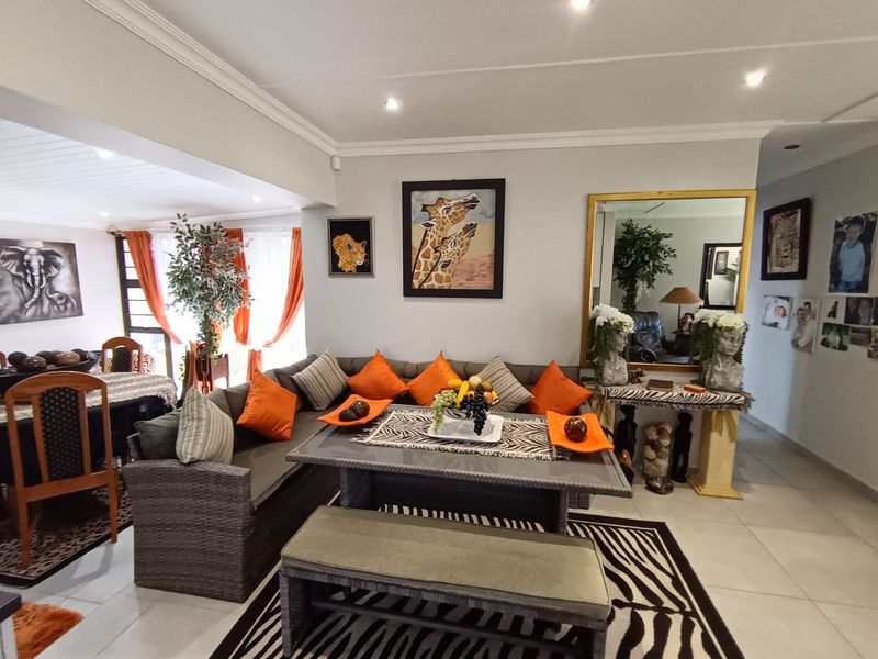 Spacious open-plan living area featuring tiled flooring, recessed downlighting, and decorative crown molding, creating a bright and functional space for relaxation and dining.
