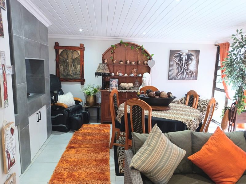 Open-plan living and dining area featuring tiled flooring, a built-in fireplace with grey tiling, and a tongue and groove ceiling with recessed lighting.