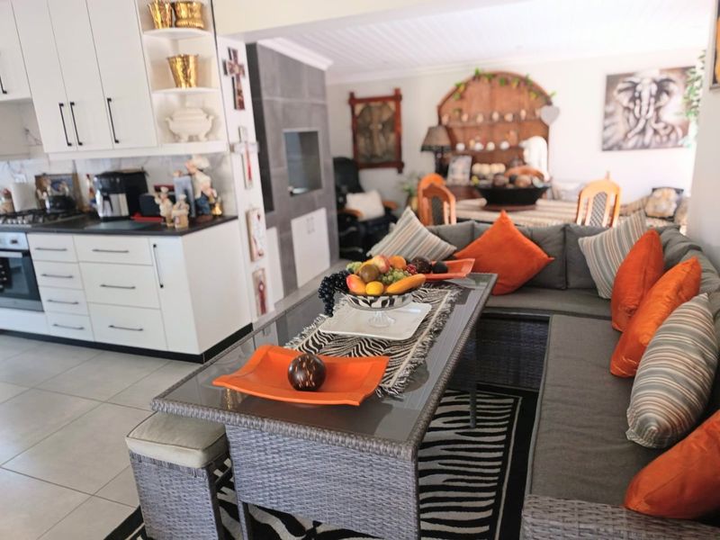 Open-plan living and kitchen area featuring modern white cabinetry, built-in oven, hob, and a fireplace, creating a functional and connected living space.