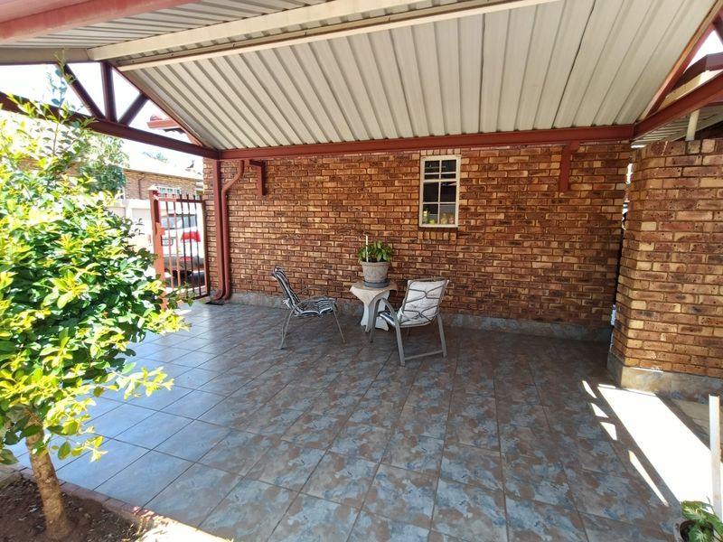 A covered outdoor patio area featuring exposed brick walls, tiled flooring, and a sturdy metal roof structure.