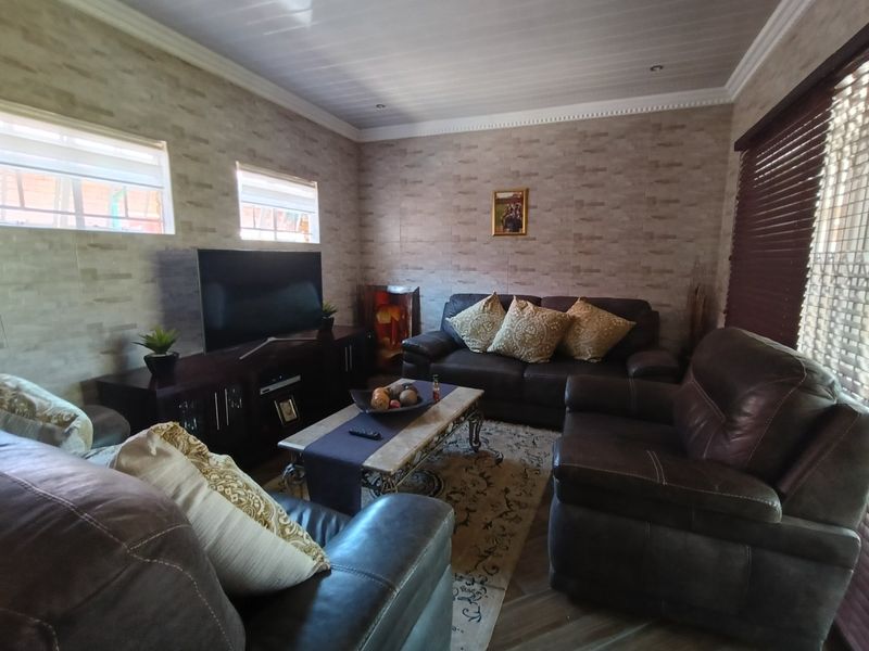 A cozy living room featuring textured wall cladding, a tongue and groove ceiling with crown molding, and venetian blinds.