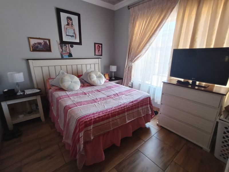 A well-maintained bedroom featuring tiled flooring and natural light through a window with curtain rails.