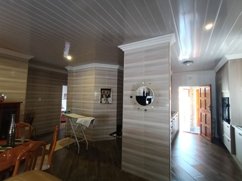 Open plan living and kitchen area featuring tiled flooring, PVC ceiling panels, and built-in cabinetry with direct access to the exterior.