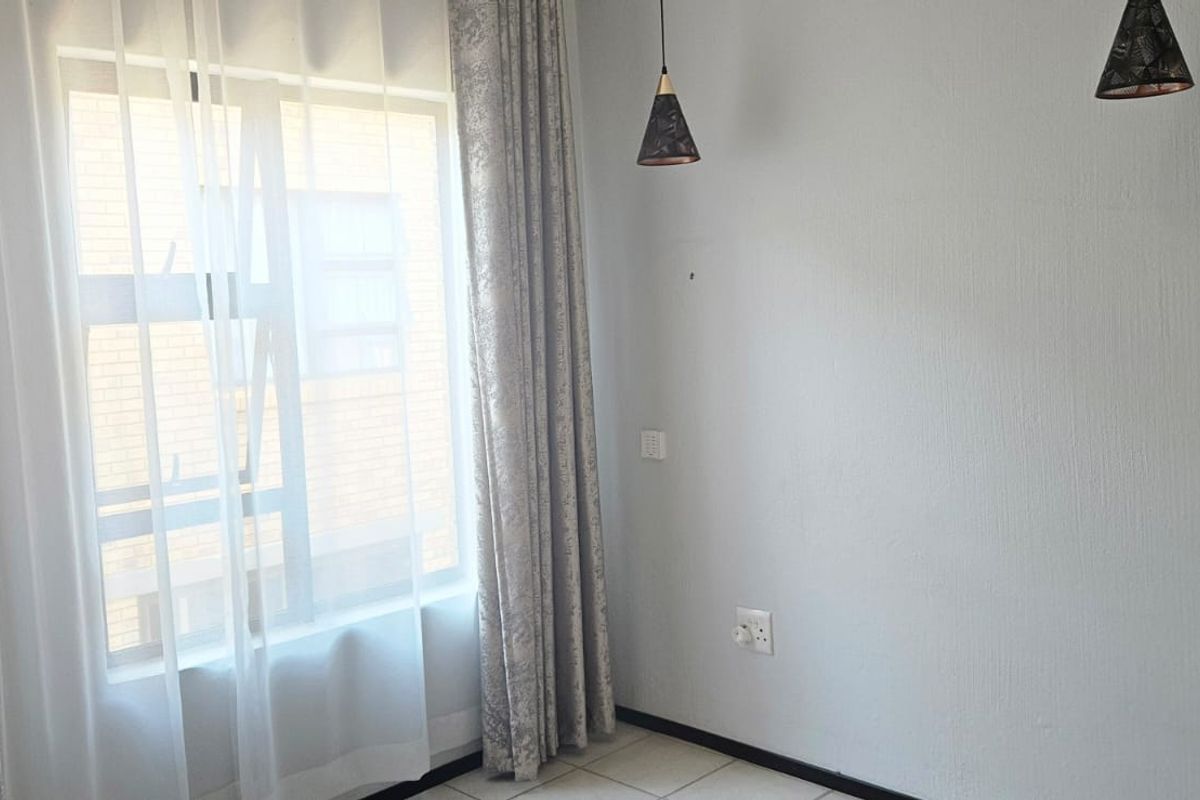 A bright, empty bedroom featuring tiled flooring, neutral walls, and modern pendant lighting, ready for personalization.