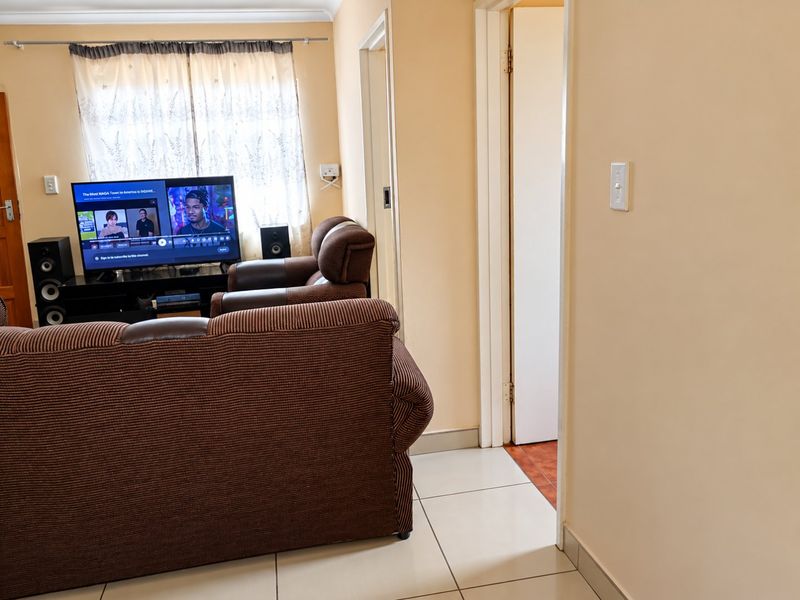 A living room featuring tiled flooring and standard finishes, providing a functional space with access to adjacent areas.