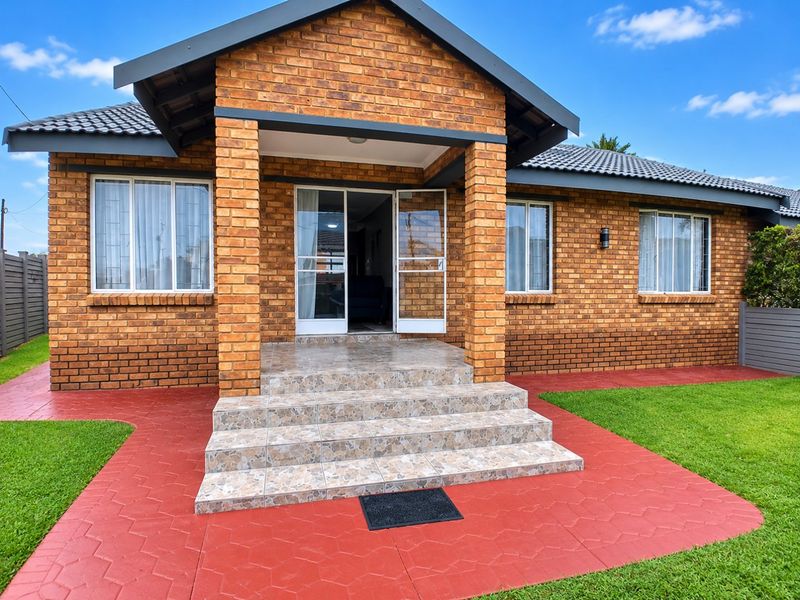 A well-maintained townhouse exterior featuring a face brick facade, tiled entrance steps, and a neat paved walkway leading to the front door.