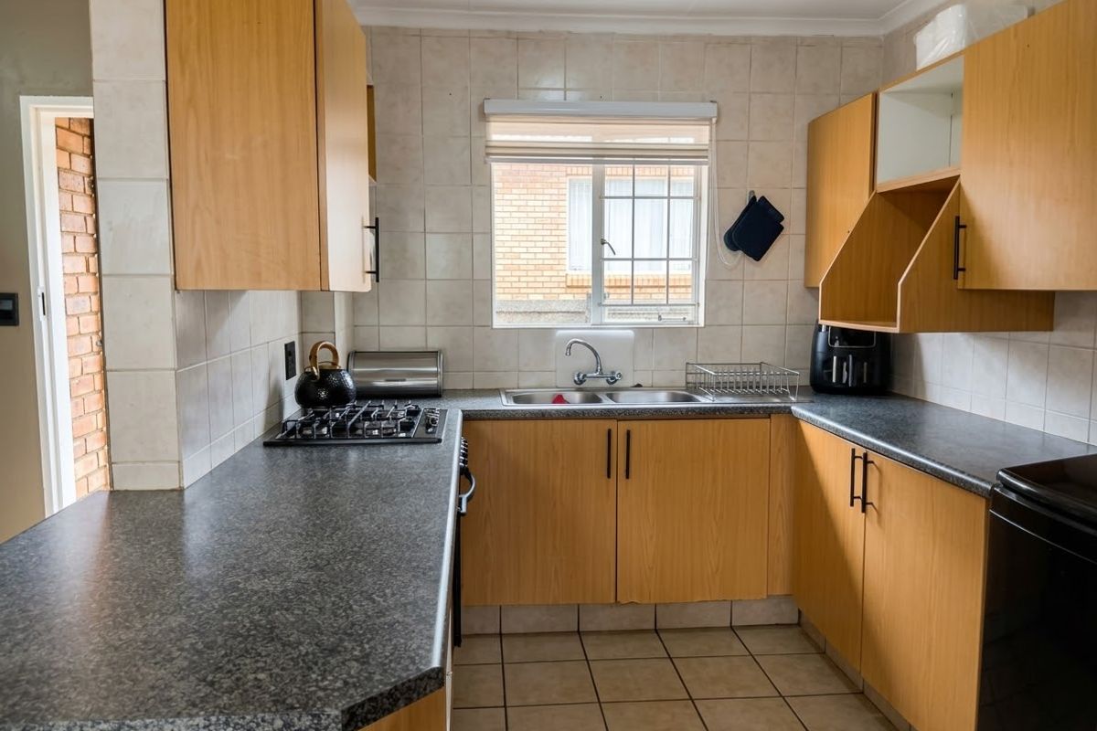 Functional kitchen featuring laminate cabinetry, granite-look countertops, a gas hob, and a double sink with tiled splashbacks.
