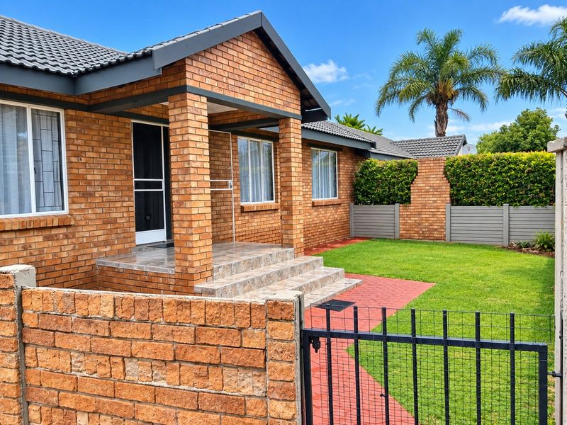 Well-maintained townhouse exterior featuring a face brick facade, covered entrance porch with tiled steps, and a neat front garden with paved walkway.