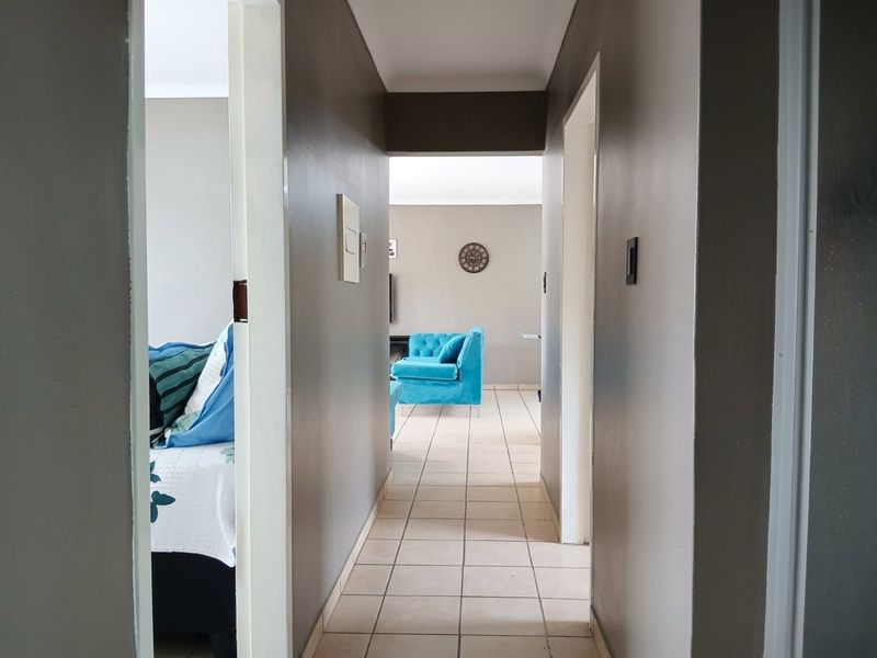 A central hallway with tiled flooring connecting the living area and adjacent rooms, featuring neutral wall tones and clean architectural lines.
