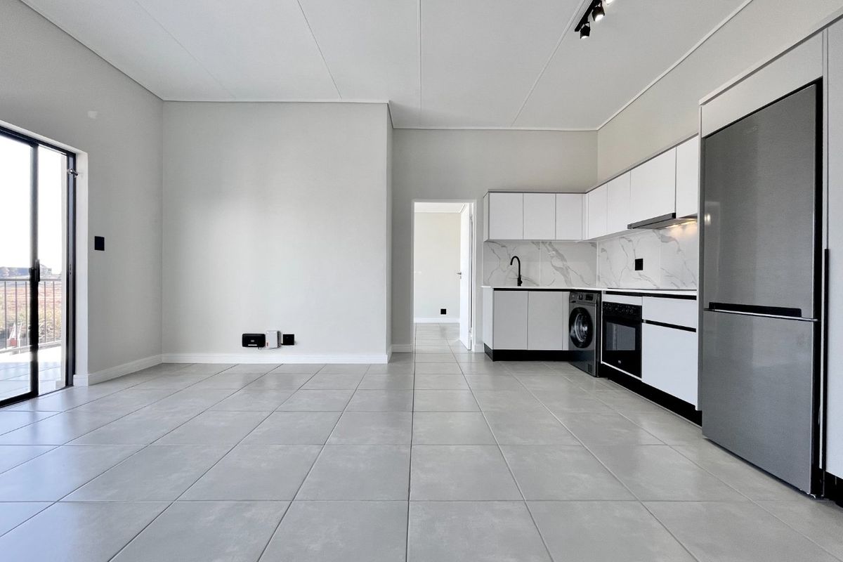 Modern open-plan living area featuring sleek tiled floors, a contemporary kitchen with marble-look backsplash, and direct access to a balcony through sliding glass doors.