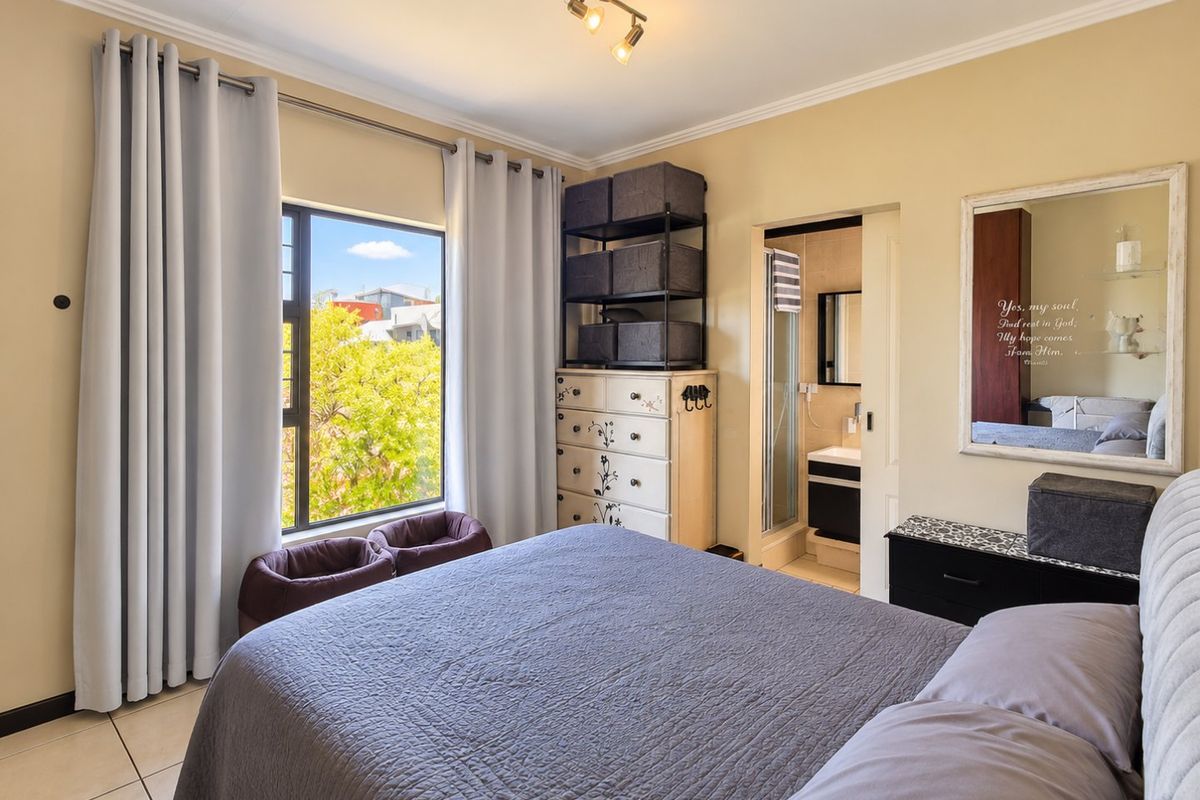 A well-maintained bedroom featuring tiled flooring, large window with natural light, and an adjoining en-suite bathroom.