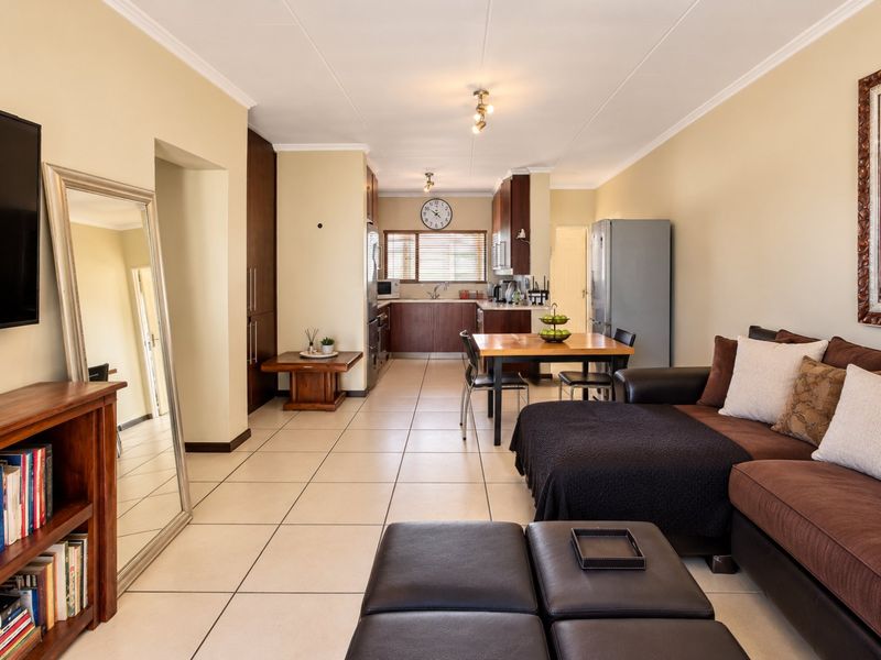 Open-plan living and kitchen area featuring tiled flooring, neutral walls, and functional built-in cabinetry, creating a cohesive and practical living space.