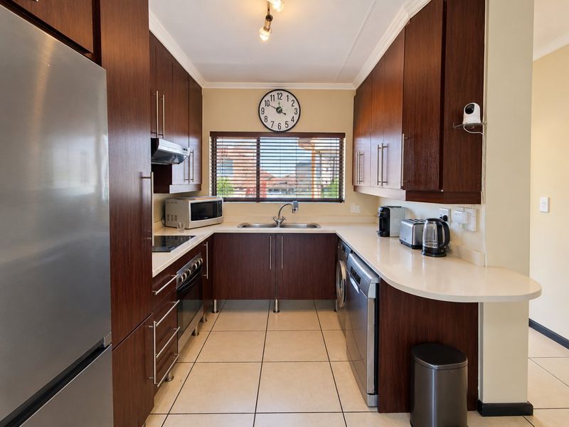 A well-maintained kitchen featuring dark wood cabinetry, stone countertops, tiled flooring, and integrated appliances, offering a functional and modern workspace.