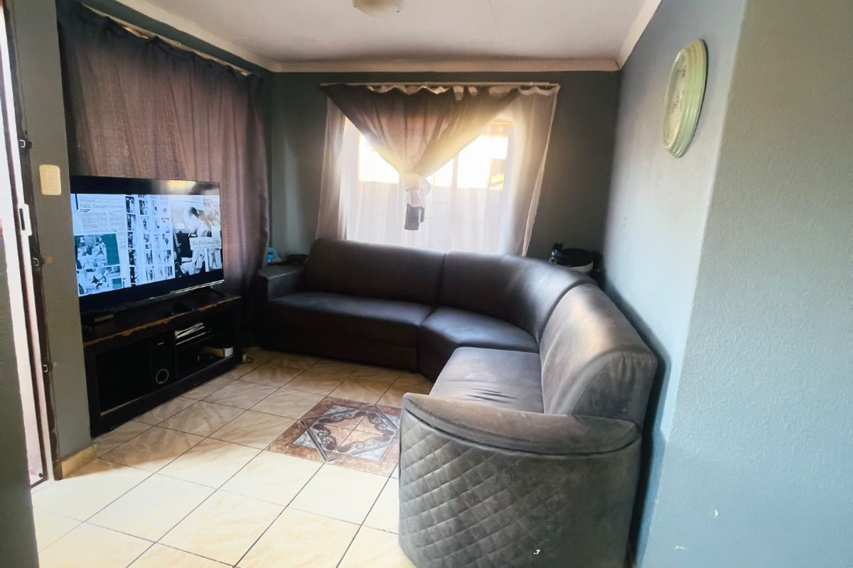 A compact living room featuring ceramic floor tiles and coved ceiling cornicing, providing a functional space for relaxation.