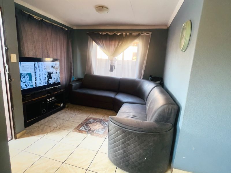 A compact living room featuring ceramic floor tiles and coved ceiling cornicing, providing a functional space for relaxation.
