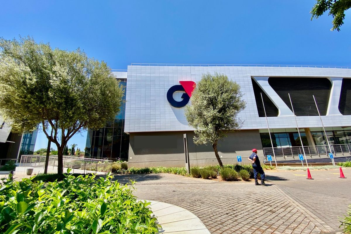 Front exterior view of a modern commercial building featuring metal cladding, glass facade elements, and a paved driveway with landscaped surroundings.