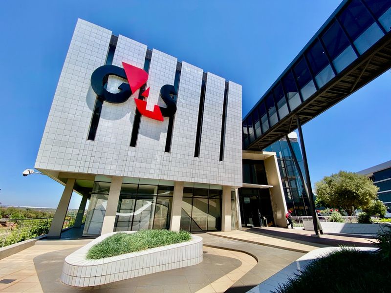 Modern commercial building exterior featuring a tiled facade, prominent signage, and an elevated glass pedestrian walkway connecting to adjacent structures.