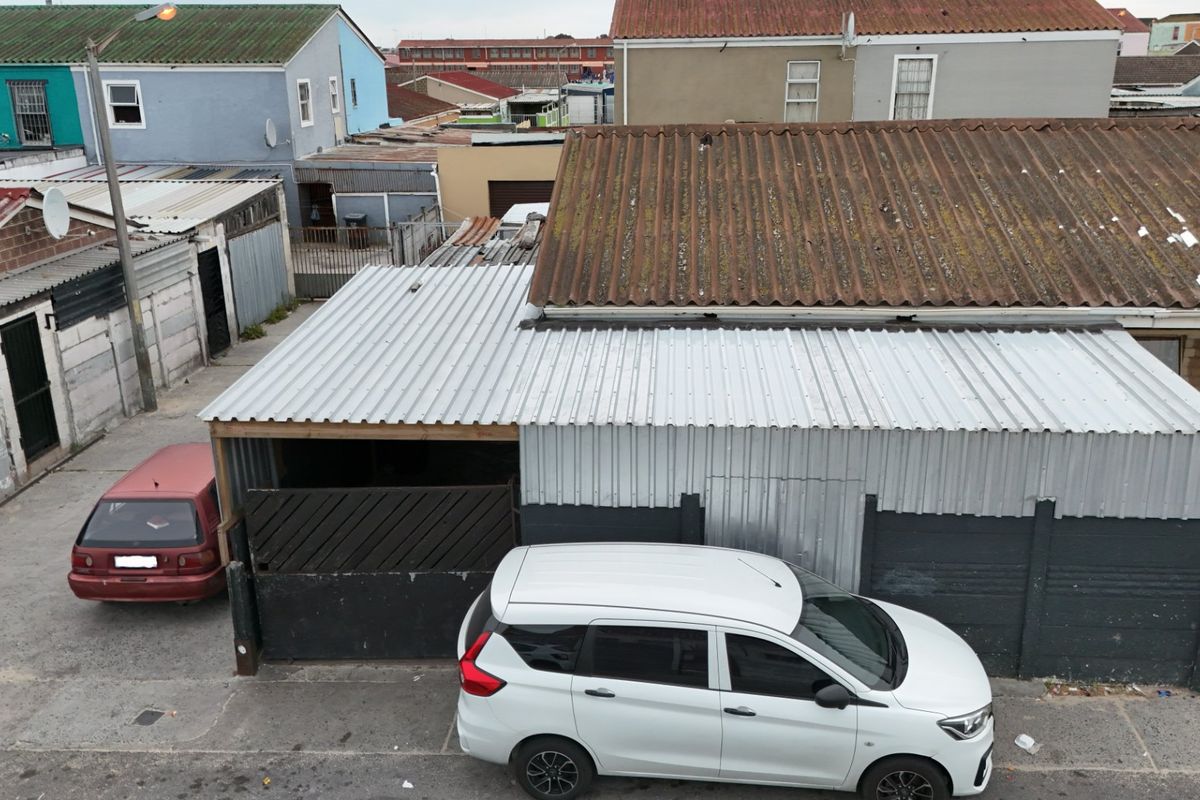 Aerial view of the property exterior showing corrugated metal roofing and concrete boundary walls in a dense residential setting.