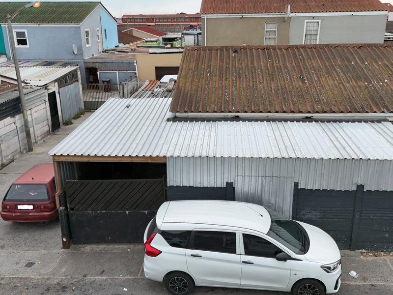 Aerial view of the property exterior showing corrugated metal roofing and concrete boundary walls in a dense residential setting.