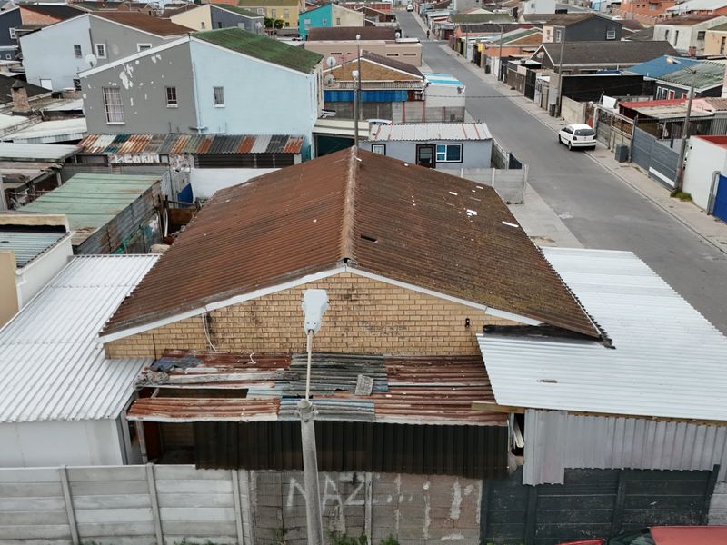 Aerial view of a residential property showing a corrugated metal roof and surrounding neighborhood context.