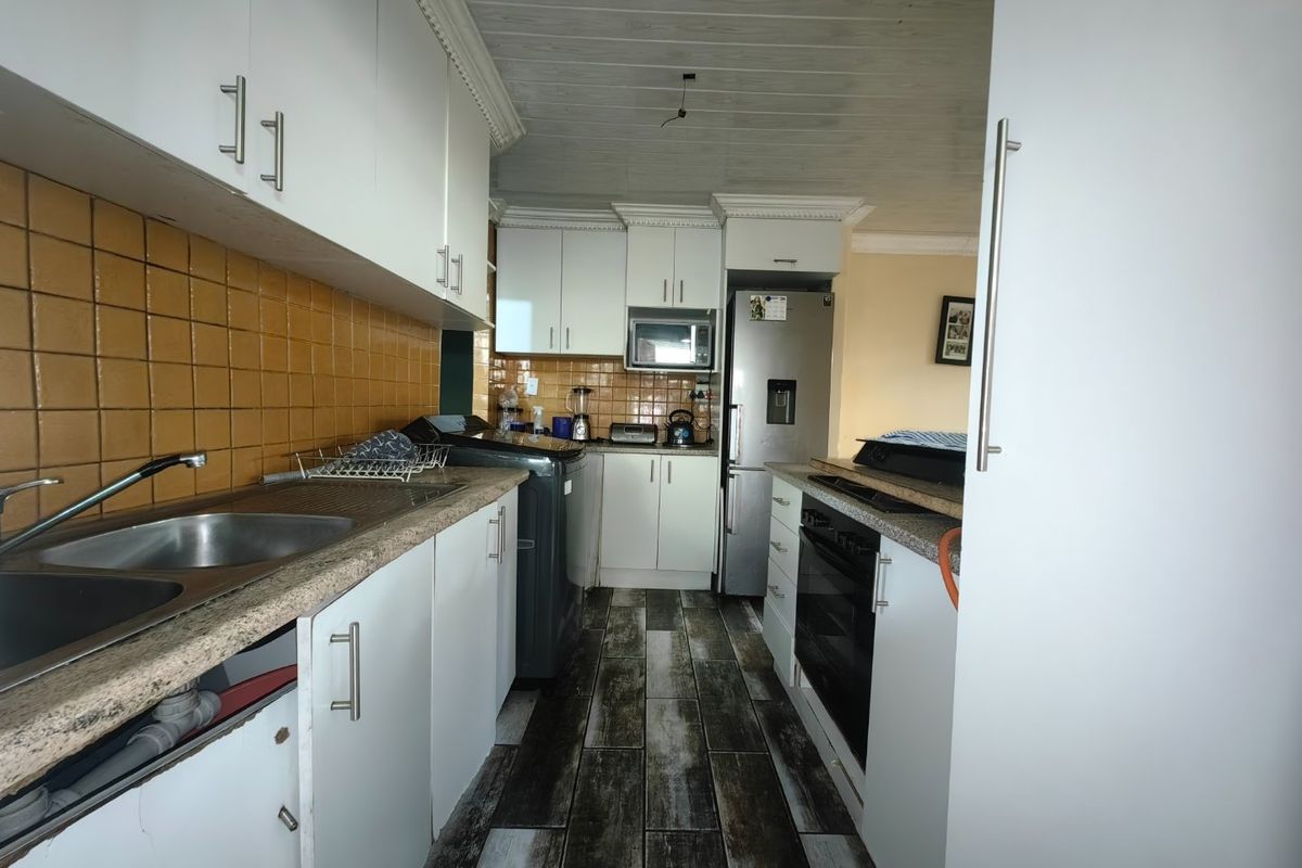 A functional kitchen featuring white cabinetry, tiled backsplash, built-in oven, and wood-look flooring, requiring minor repairs to cabinetry and ceiling fixtures.