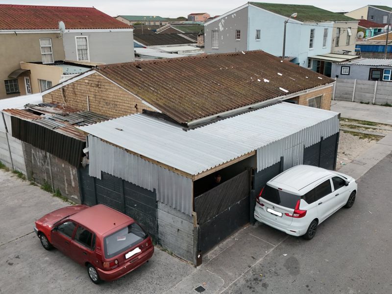 Aerial view of a residential property featuring a corrugated metal roof and brick exterior, showing significant signs of wear and maintenance requirements.