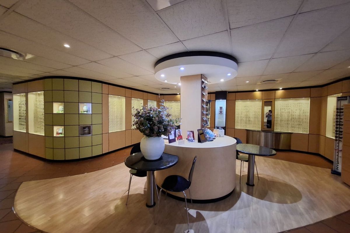 Commercial retail space featuring a central circular service counter, extensive built-in display cabinetry, and recessed ceiling lighting.