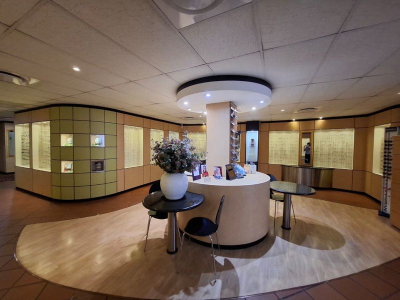 Commercial retail space featuring a central circular service counter, extensive built-in display cabinetry, and recessed ceiling lighting.