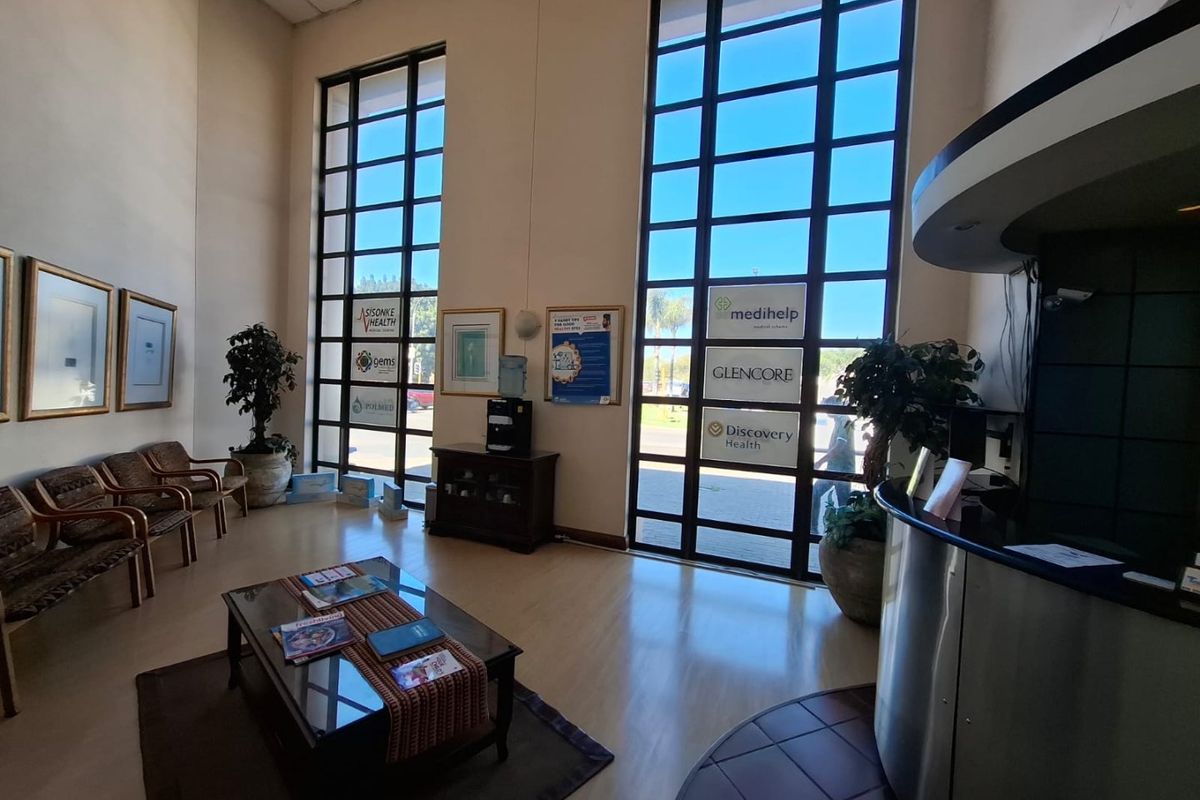 A bright and spacious commercial reception area featuring high ceilings, large floor-to-ceiling windows, and a modern reception desk.