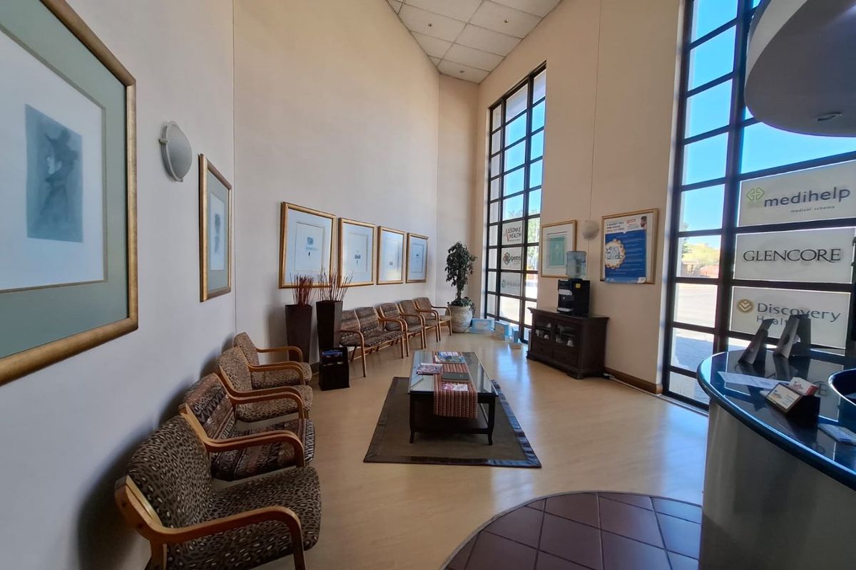 Spacious commercial reception area featuring double-height windows, laminate flooring, and a dedicated reception desk, providing a bright and professional entrance space.