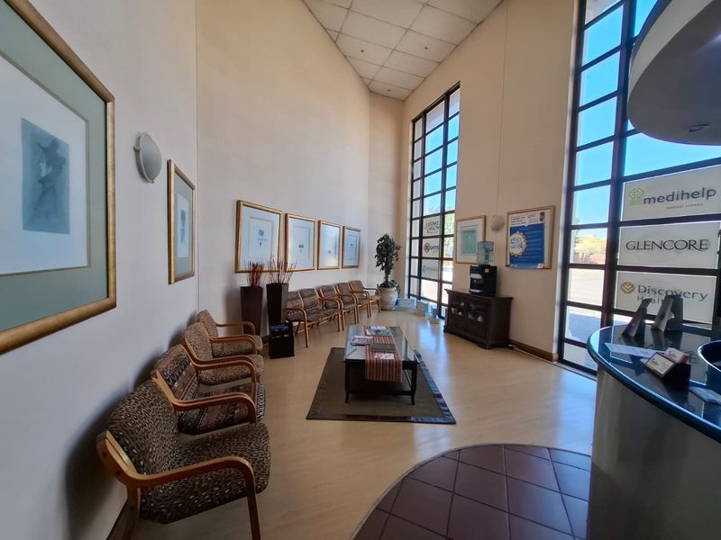 Spacious commercial reception area featuring double-height windows, laminate flooring, and a dedicated reception desk, providing a bright and professional entrance space.