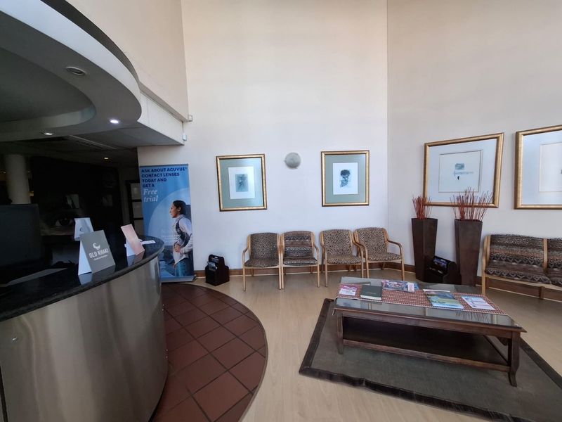 A commercial reception area featuring a curved reception desk, high ceilings, and a combination of tiled and laminate flooring.