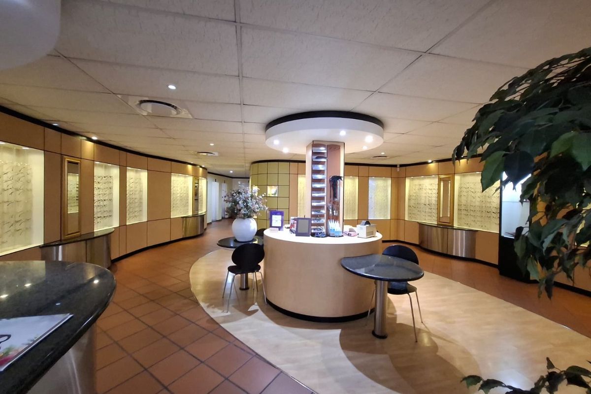 Commercial retail space featuring a central circular service counter, extensive built-in wall display cabinetry, and recessed ceiling lighting throughout the interior.