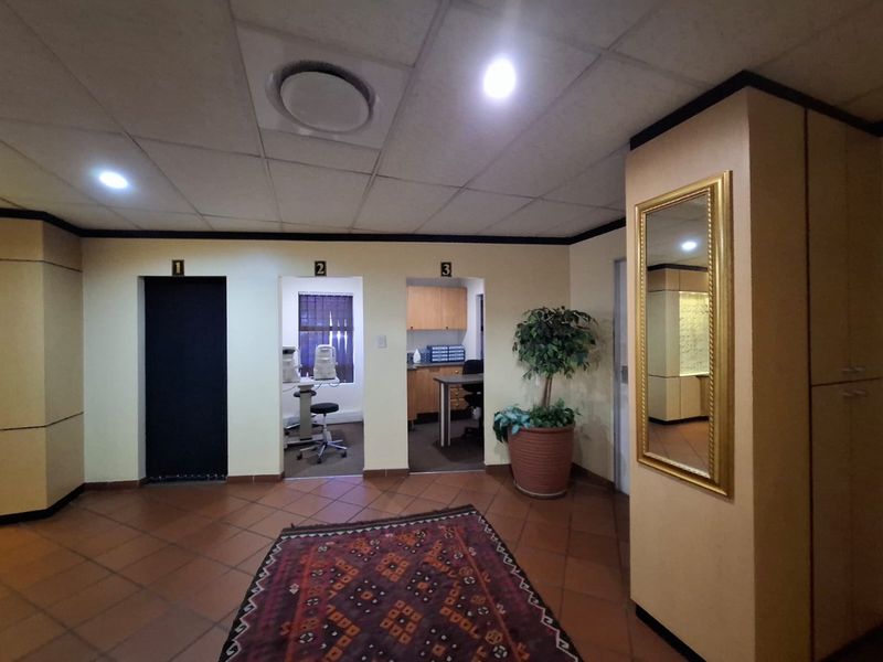 Commercial office space featuring a central waiting area with numbered consultation rooms, terracotta flooring, and integrated cabinetry.