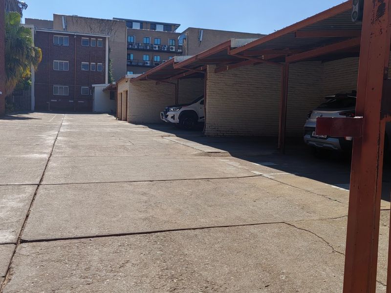 Outdoor covered parking area with concrete paving and brick walling, providing dedicated vehicle storage for the apartment complex.