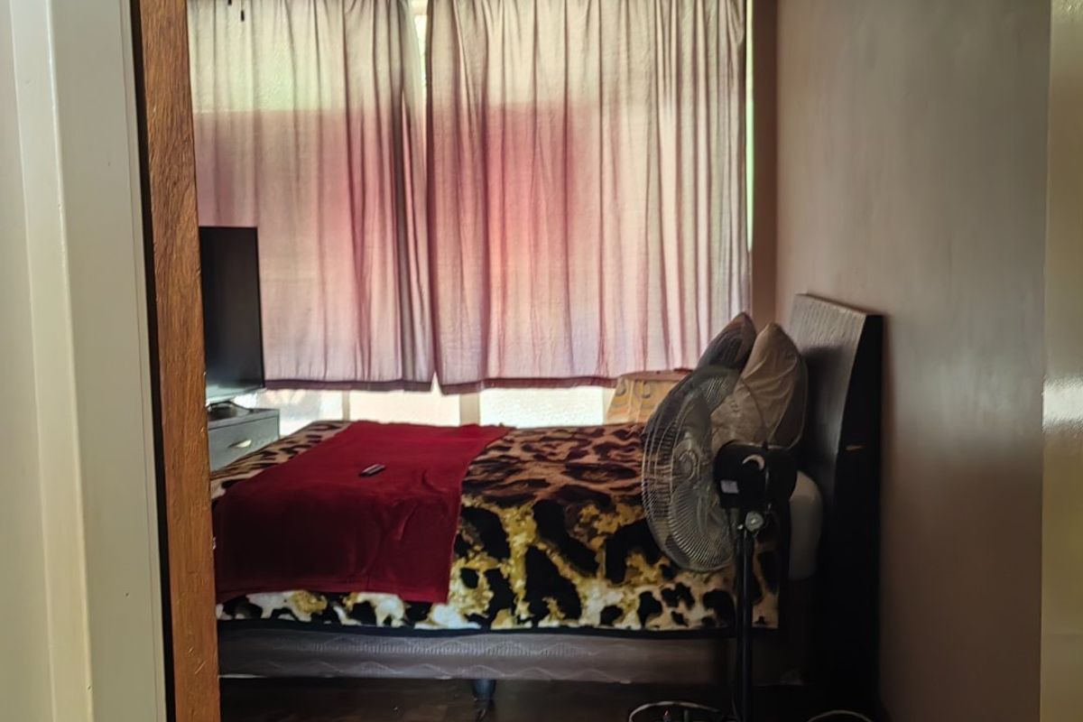 A bedroom featuring parquet flooring and a ceiling fan, viewed from the doorway.