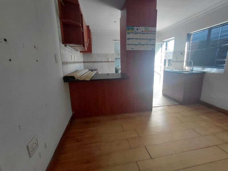An empty kitchen featuring built-in cabinetry, a breakfast bar, and a tiled backsplash, requiring cosmetic updates to improve its overall condition.