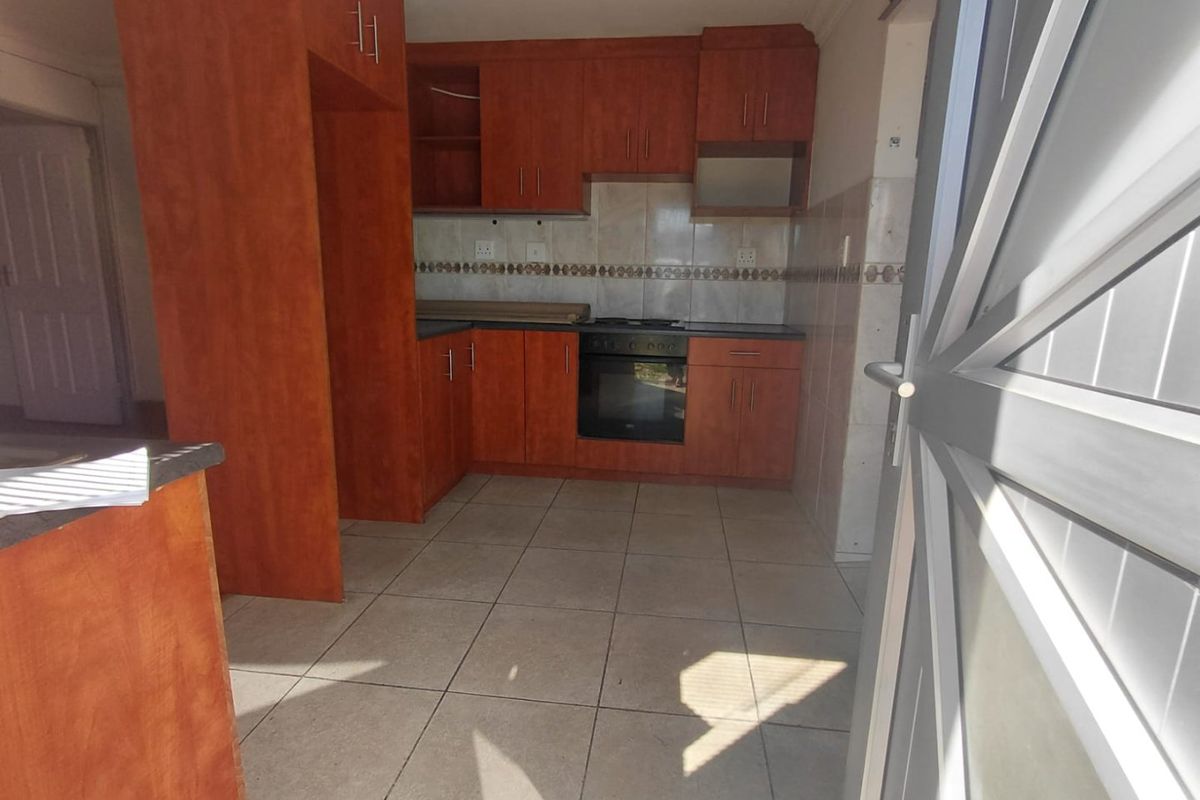 A functional kitchen featuring built-in wooden cabinetry, tiled flooring, a tiled backsplash, and a built-in oven with a hob.