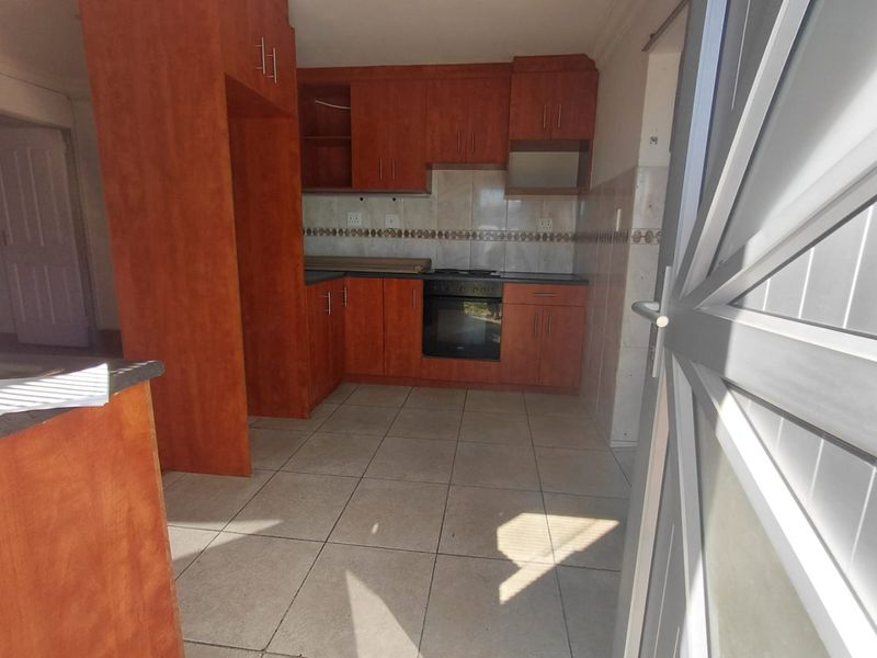 A functional kitchen featuring built-in wooden cabinetry, tiled flooring, a tiled backsplash, and a built-in oven with a hob.