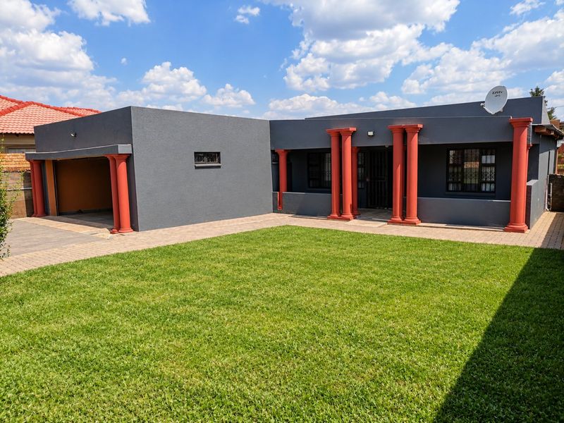 Front elevation of a modern house featuring a paved driveway, integrated garage, and decorative columns framing the entrance.