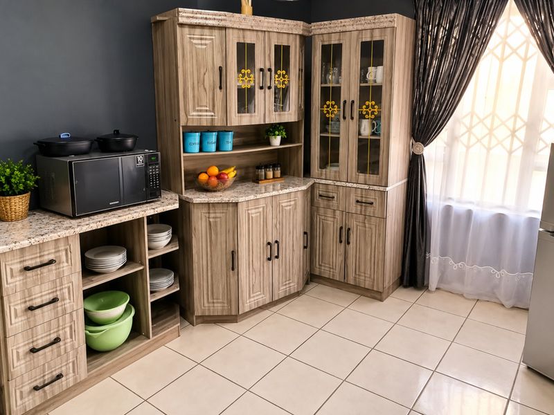 A well-maintained kitchen featuring wood-grain cabinetry, granite countertops, and ceramic floor tiles, offering ample storage and a functional layout.