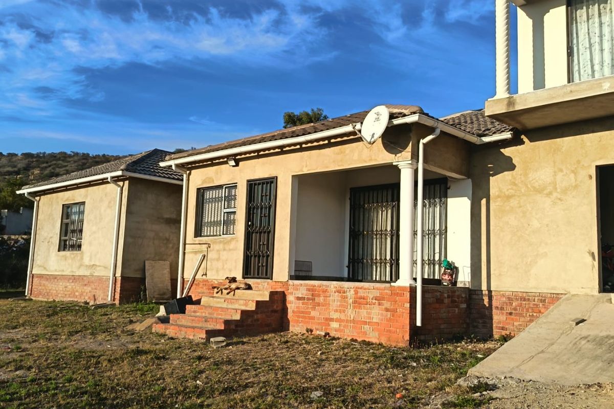 Rear view of a house featuring a covered patio, brick plinth foundation, and unfinished exterior wall plastering.