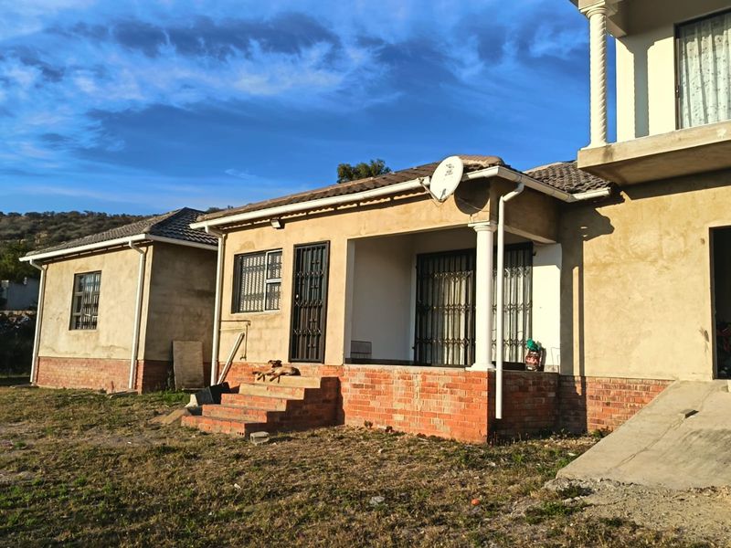 Rear view of a house featuring a covered patio, brick plinth foundation, and unfinished exterior wall plastering.